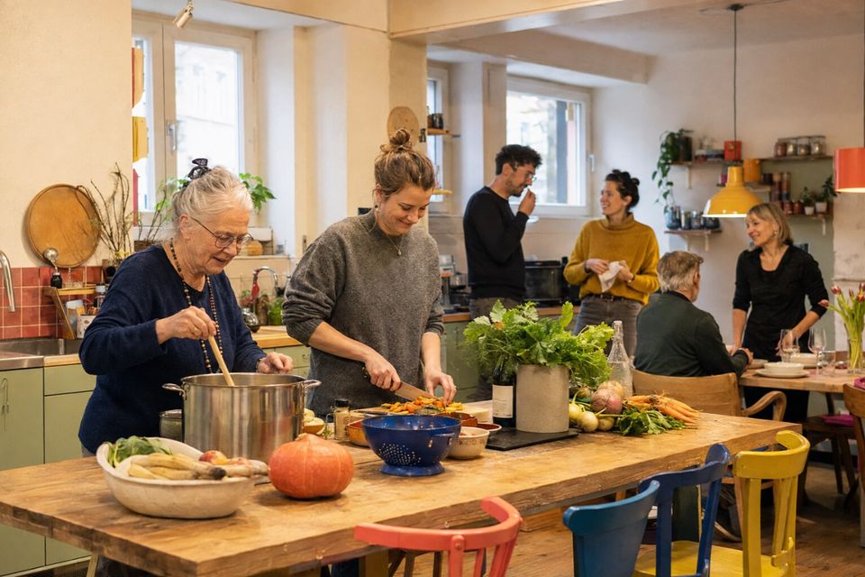 Unverbindliche KI-Konzeptvisualisierung einer warmen Gemeinschaftsküche, in der ältere und jüngere Nachbarn zusammen kochen.